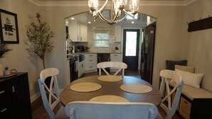 A dining area with a round table, four chairs, and a chandelier. - Cozy Greenville Cottage. Close to downtown! Pet friendly! (Greenville)