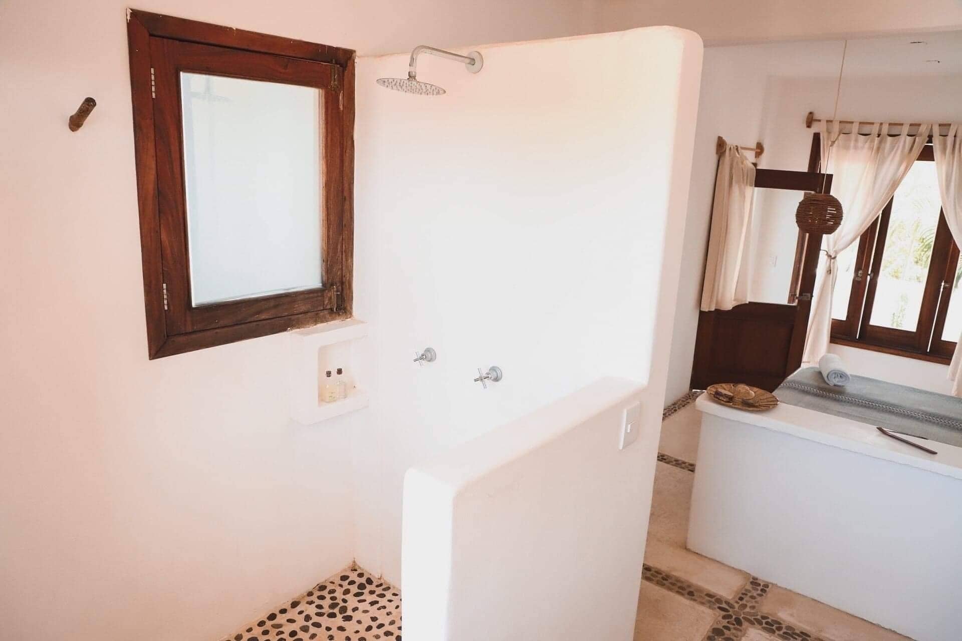 Ein Badezimmer mit Dusche, Spiegel und einem blickdichten Fenster.