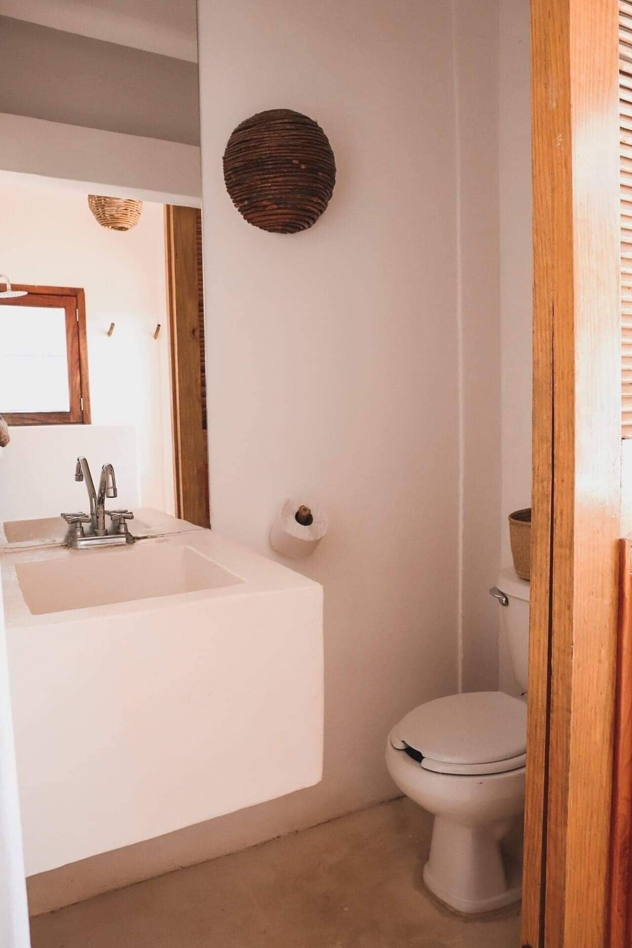 A bathroom with a white sink, a toilet, and a wooden wall decoration.