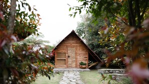 A wooden cabin with a stone pathway leading to it, surrounded by greenery. - Hostal La Laguna (Villamaria)