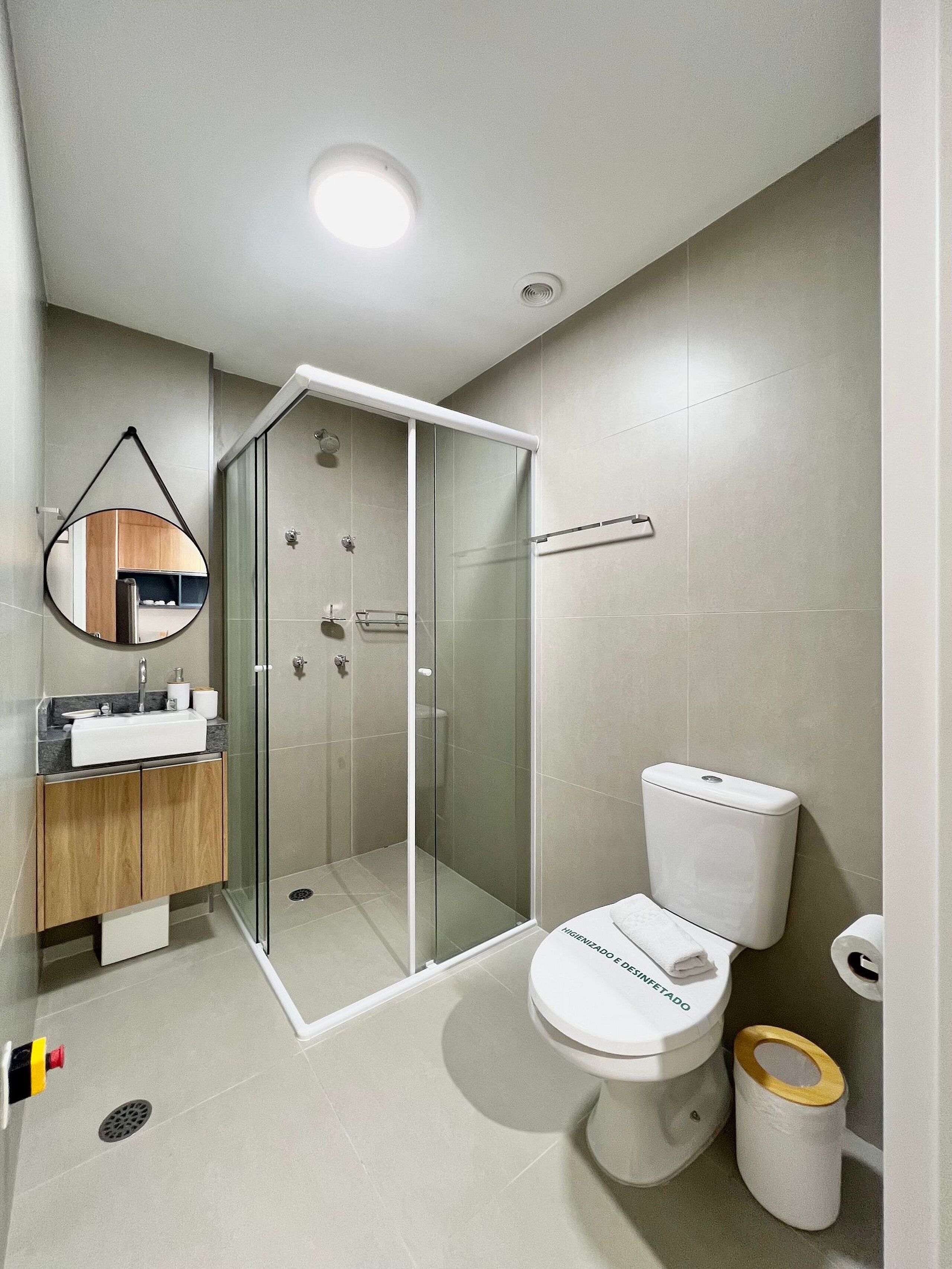 A modern bathroom with a glass-enclosed shower, a toilet, and a sink with a mirror above it.