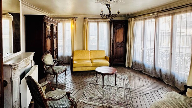 A spacious room with a yellow sofa, wooden chairs, a round table, and a patterned rug. - Cosy and charming 2bed appartement in the Center PARIS marais (Paris)