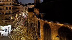 A nighttime view of a cityscape with illuminated buildings, a prominent tower, and a crescent moon. - Cosy and charming 2bed appartement in the Center PARIS marais (Paris)
