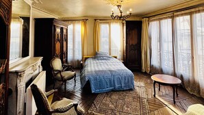 A spacious bedroom with a large bed, a sitting area with chairs, a fireplace, and a chandelier. - Cosy and charming 2bed appartement in the Center PARIS marais (Paris)