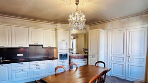 A spacious kitchen with white cabinets, a wooden dining table, and a chandelier. - Cosy and charming 2bed appartement in the Center PARIS marais (Paris)