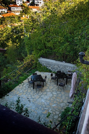 A stone patio with outdoor furniture, surrounded by lush greenery and a stone wall. - Meltem Hanım Konagı (Karabuk)