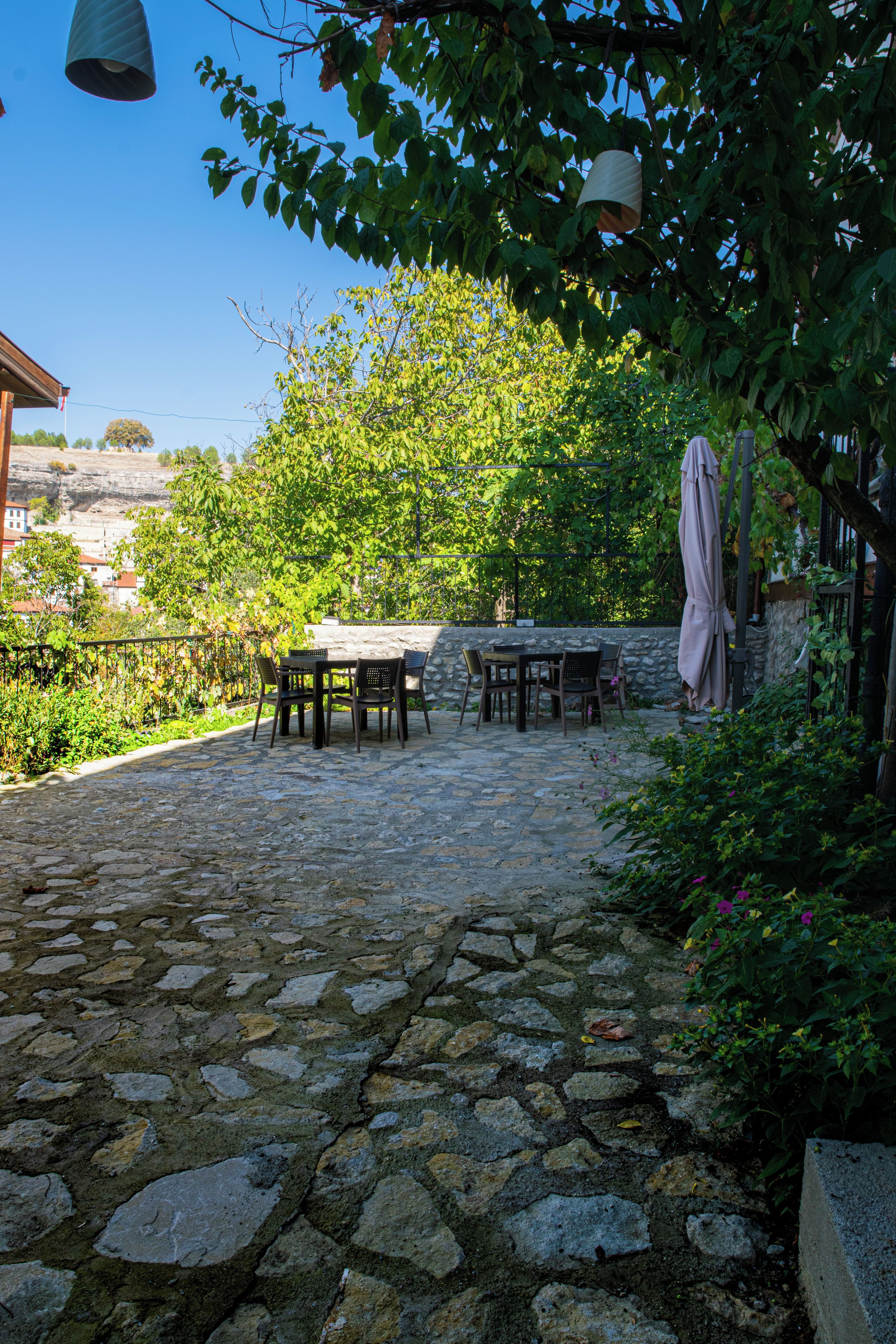 An outdoor patio with stone flooring, a table with chairs, and a pergola with a canopy.