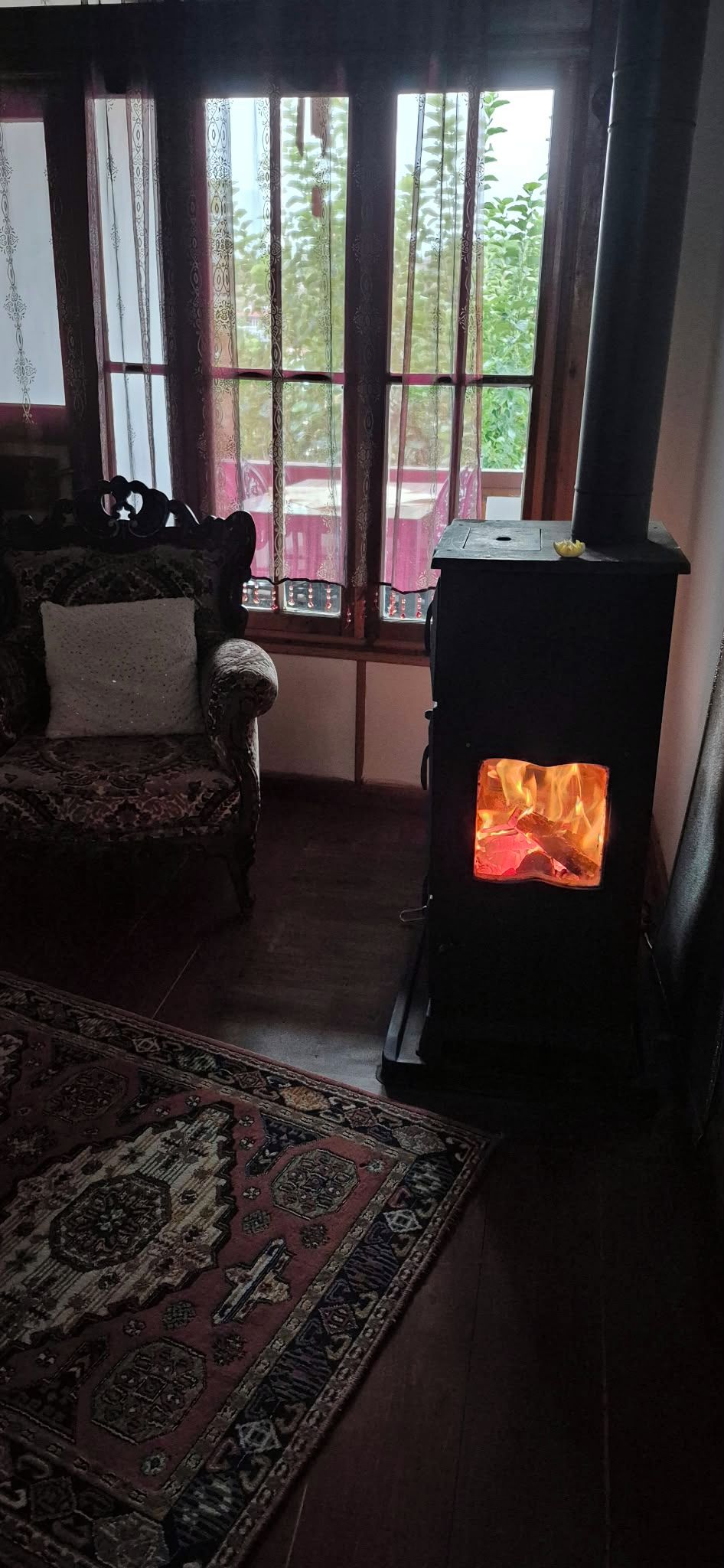 A room with a traditional fireplace, a patterned rug, and a window with curtains.