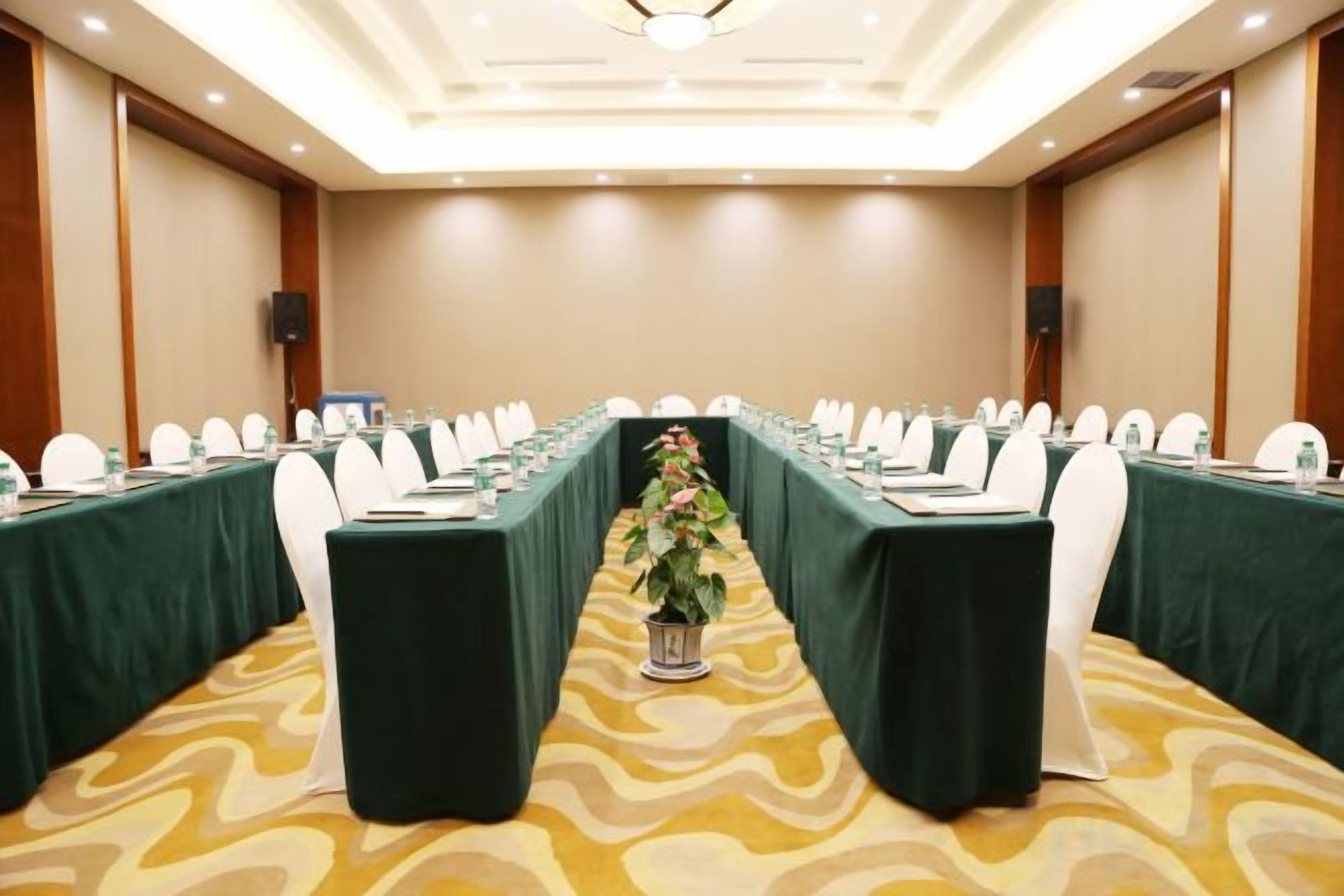 A conference room with a long table, chairs, and a plant in the center.