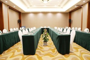 A conference room with a long table, chairs, and a plant in the center.