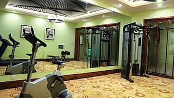 A gym with exercise equipment, a mirror, and a patterned carpet.