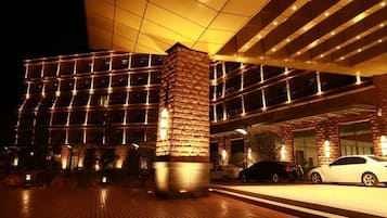 A modern hotel with a prominent stone pillar, large windows, and a well-lit entrance area.