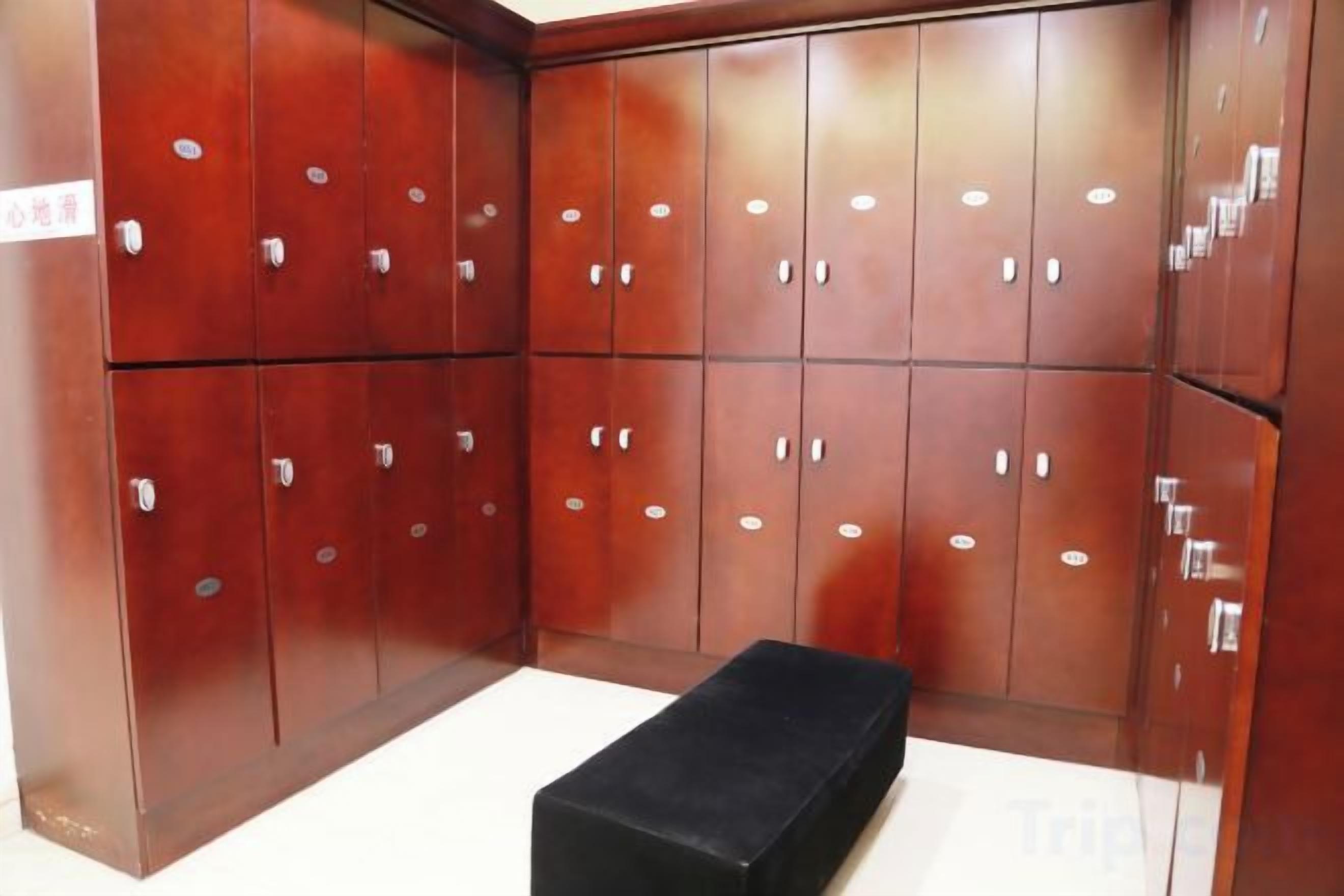 Quarto com um banco preto, armários de madeira e piso de azulejos.
