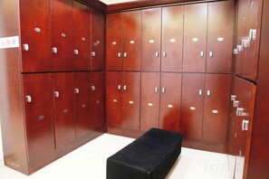 Una habitación con un banco negro, taquillas de madera y suelo de baldosas.