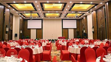 A banquet hall with round tables, red chairs, and a carpeted floor.