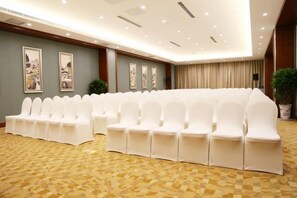 A conference room with rows of white chairs, a patterned carpet, and framed artwork on the walls. - Tiantai Yunjie International Hotel (Xiuwu)