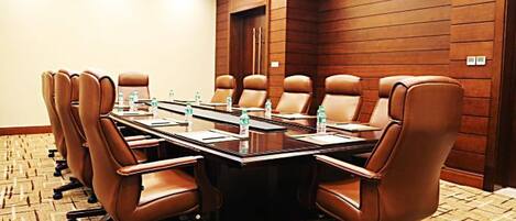 A conference room with a long table, brown leather chairs, and a carpeted floor.