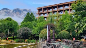 A hotel with outdoor seating, a pool, and a view of mountains. - Tiantai Yunjie International Hotel (Xiuwu)
