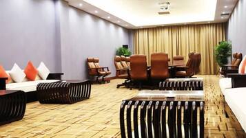 Una sala de conferencias con una mesa grande, múltiples sillas y piso alfombrado.