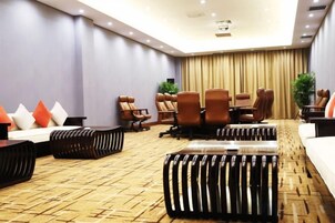 Una sala de conferencias con una mesa grande, múltiples sillas y piso alfombrado.