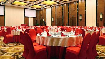 Un salón de banquetes con mesas redondas, sillas rojas y piso alfombrado.