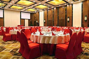 Un salón de banquetes con mesas redondas, sillas rojas y piso alfombrado.