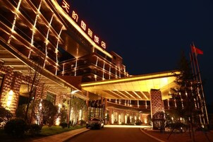 A hotel with a modern architectural design, featuring a prominent entrance and a well-lit facade.