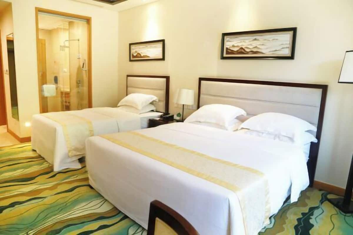 A hotel room with two beds, a shower, and artwork on the walls.