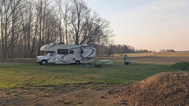 Un veicolo ricreativo (RV) parcheggiato in un prato erboso con alberi sullo sfondo.