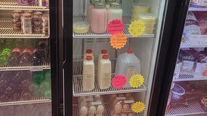 Una vetrina refrigerata con diversi prodotti lattiero-caseari e bevande, tra cui latte, yogurt e succo di frutta.