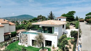 Une villa moderne dotée d’une piscine, de grandes fenêtres et offrant une vue sur le paysage environnant.