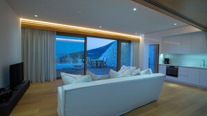 Ein modernes Wohnzimmer mit einer großen weißen Couch, einem Flachbildfernseher und einem Essbereich mit Tisch und Stühlen.