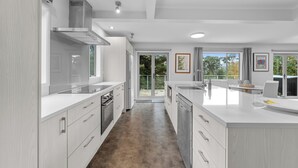 Une cuisine moderne dotée d’un îlot central, de portes coulissantes donnant sur un patio et offrant une vue sur la verdure environnante.