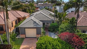 A residential area with houses featuring red-tiled roofs and a central garage. - Beachside 24 - Pet Friendly Holiday Home - Holiday Yamba (Yamba)