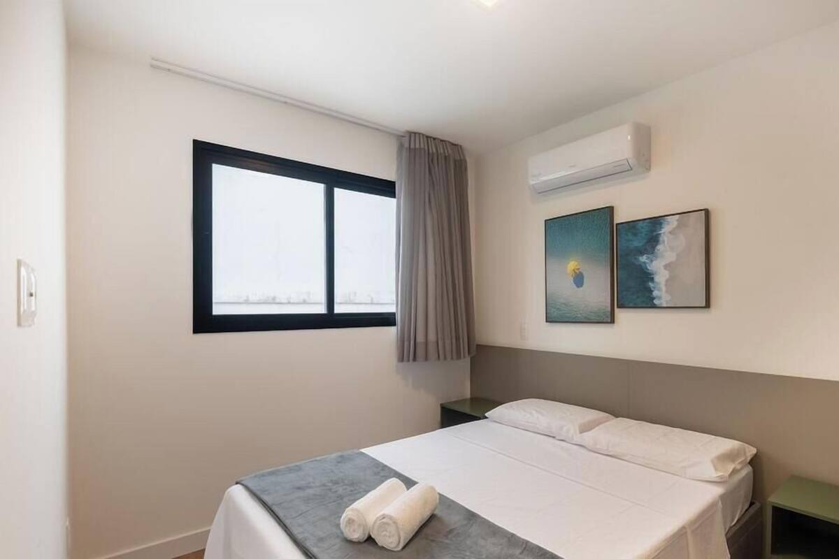 Ein Schlafzimmer mit einem Bett, einem Fenster, einer Klimaanlage und zwei Wandbildern.
