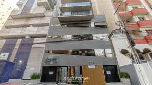 Un immeuble à plusieurs étages doté d’une architecture moderne, avec des balcons et une entrée imposante.