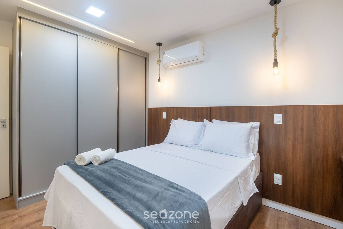Ein Schlafzimmer mit einem Bett, einem hölzernen Kopfteil, einer Klimaanlage und einer Wandleuchte.