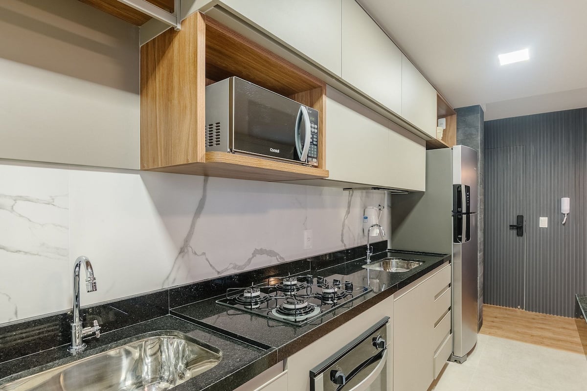 Eine moderne Küche mit eingebauter Mikrowelle, Edelstahlgeräten und einer Marmor-Spritzschutzwand.