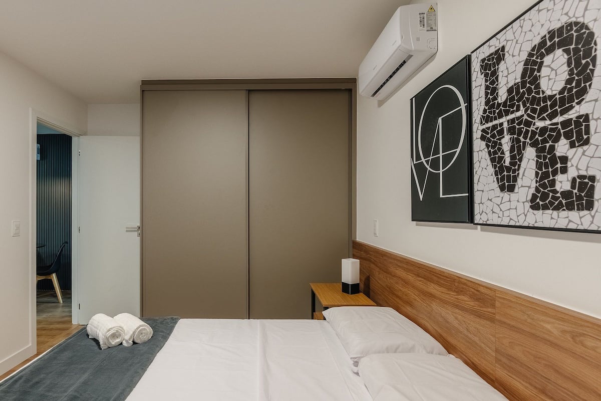 Ein Hotelzimmer mit Bett, Nachttisch, Klimaanlage, einer Tür und einer Wand mit Mosaikkunst.