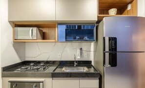 A modern kitchen with a built-in microwave, gas stove, stainless steel refrigerator, and a window above the sink.