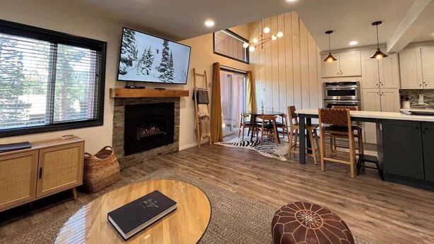 Un salon moderne doté d’une cheminée, d’un coin repas et d’une cuisine avec des meubles en bois.