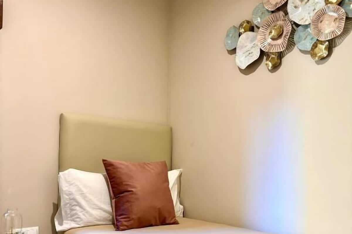 Une chambre à coucher avec un lit, des oreillers, une table de chevet et un élément décoratif mural.