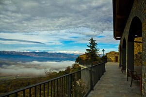 Un sendero de piedra que lleva a un balcón con vistas a montañas y nubes.