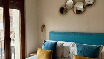 Habitación de hotel con cama, cabecera azul y tres espejos redondos en la pared.