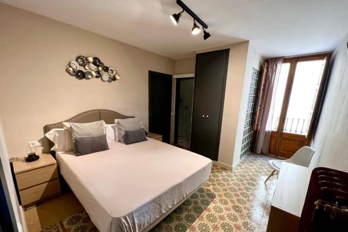 Une chambre à coucher avec un lit, une table de chevet et un bureau.