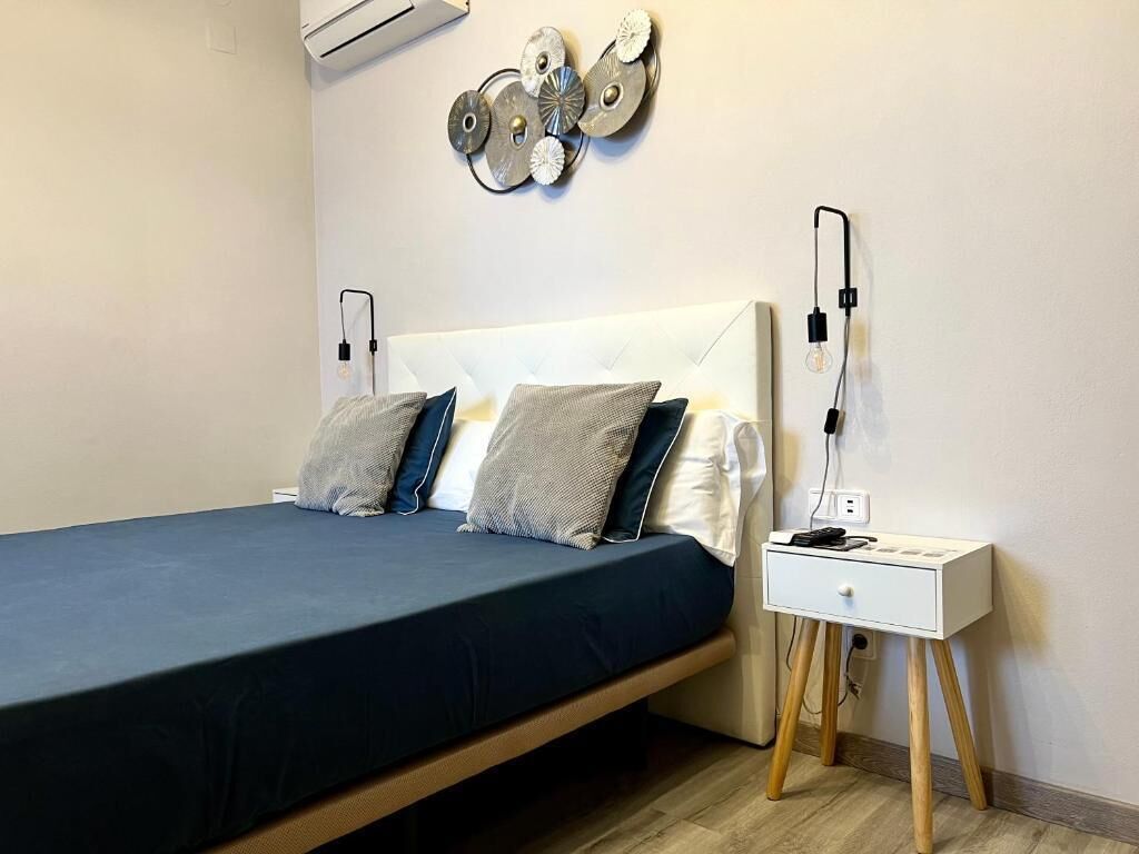 Quarto bem arrumado com cama, mesa de cabeceira e arte decorativa na parede.