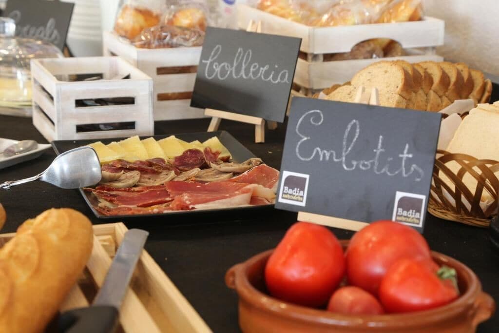 A buffet table with various food items including bread, cheese, and tomatoes.