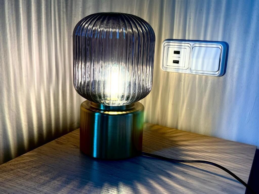 En lampe med en rillet overflade på en træplade, tilsluttet en stikkontakt.