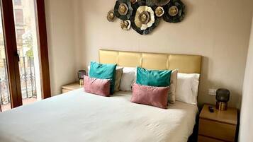 A hotel room with a large bed, two nightstands, a decorative wall piece, and a view through a window.