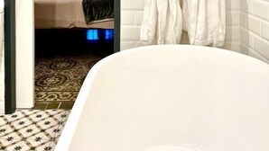 A hotel room with a bed, a bathroom with a bathtub, and a view of the city through the window.